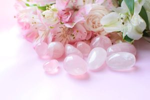 Kryształy różowego kwarcu oraz bukiet róż i alstremerii. Kryształy lecznicze, magia kamieni szlachetnych.